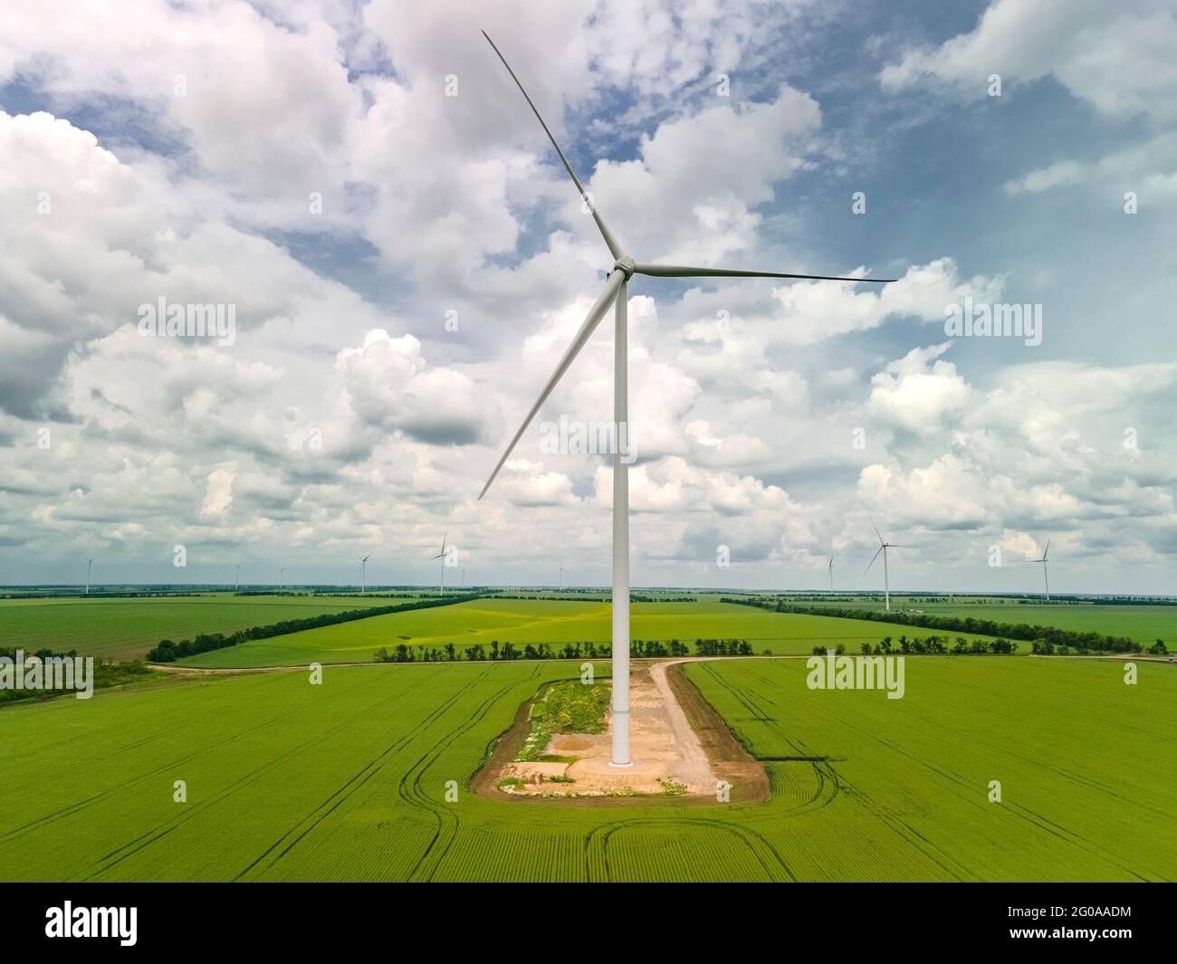 Turbine eoliche sul campo verde e cielo blu stupefacente con le nuvole. Energia ecologica Foto Stock