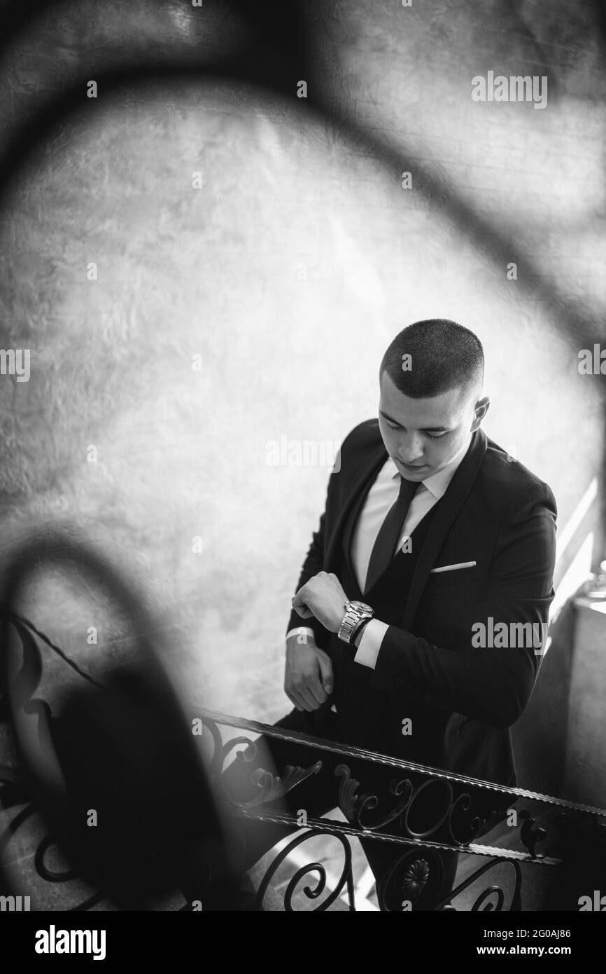 Scatto verticale di un bel maschio caucasico con un vestito che salirà le scale Foto Stock