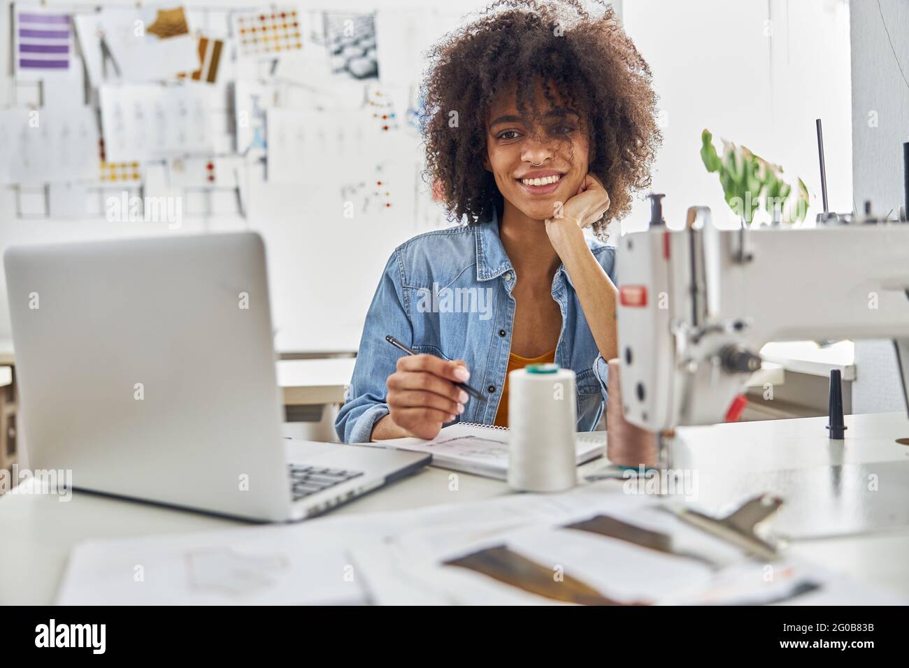 Dressaker afroamericano disegna guardare la lezione online via computer portatile in studio luce Foto Stock