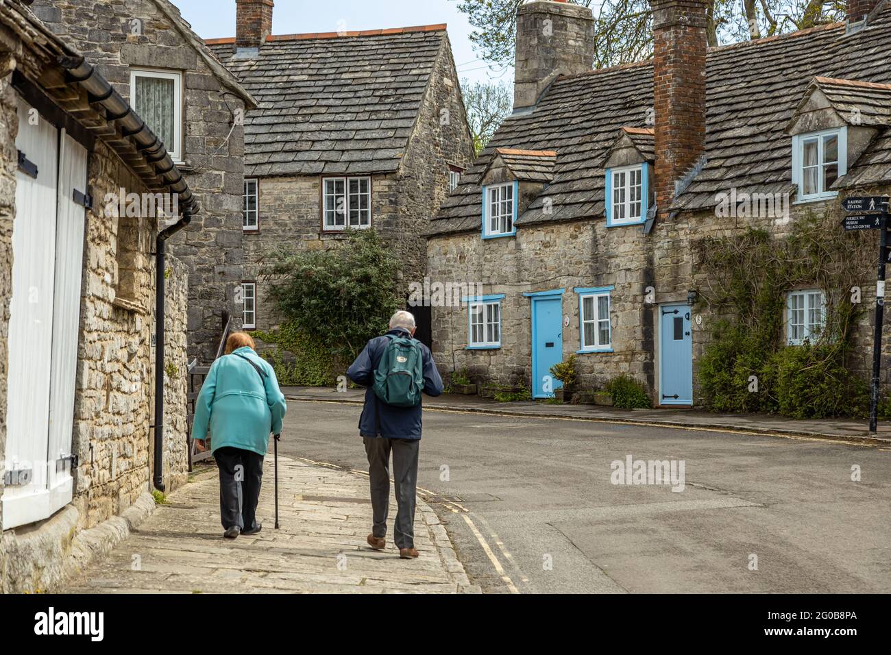 Una coppia anziana cammina attraverso il pittoresco, idilliaco e pittoresco villaggio di Corfe, originariamente una roccaforte sassone nelle colline di Purbeck, Dorset Inghilterra UK Foto Stock