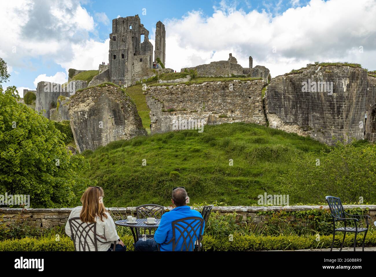Una coppia si rilassa e gustatevi una tazza di te' con la gloriosa vista del paesaggio del Corfe Castle Dorset England UK in un luminoso pomeriggio Foto Stock