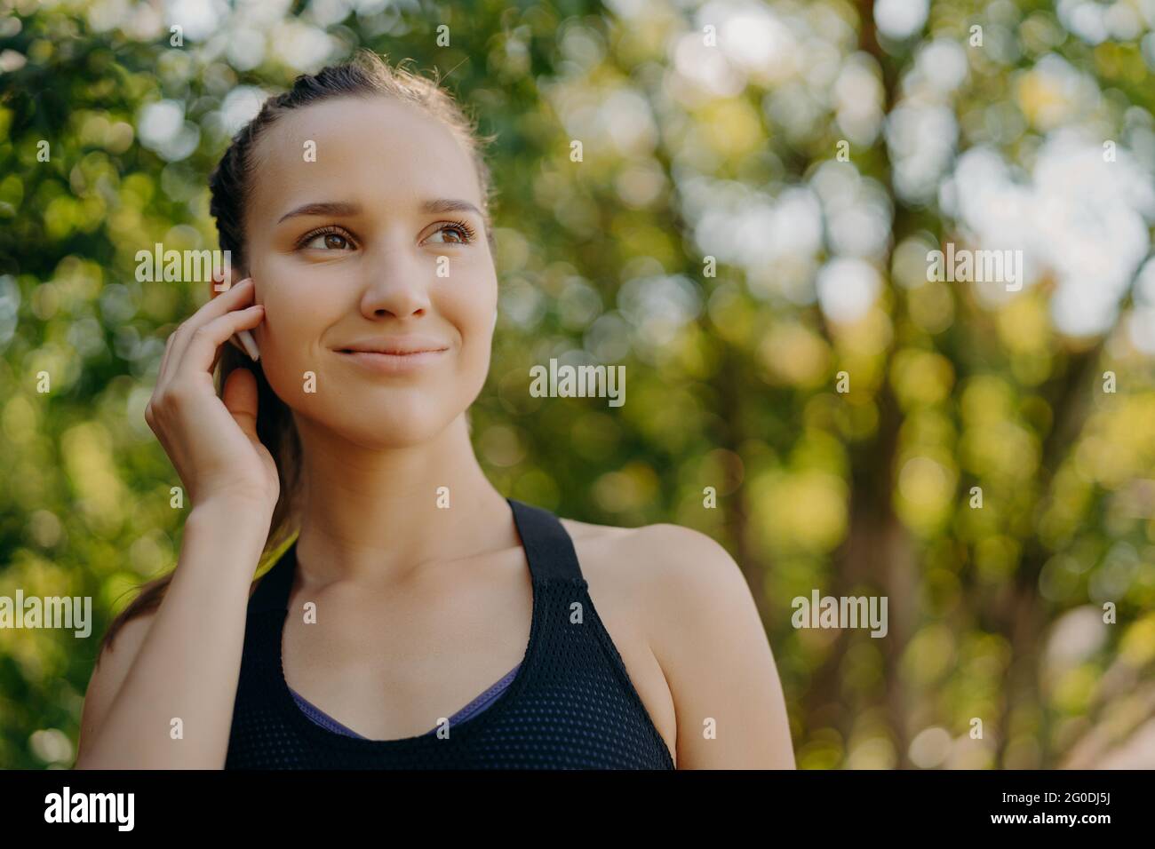 Le riprese sportive all'aperto si divertono con la playlist preferita degli auricolari, mentre l'allenamento nel parco ha un sorriso delicato concentrato in posizioni lontananza sfocate Foto Stock
