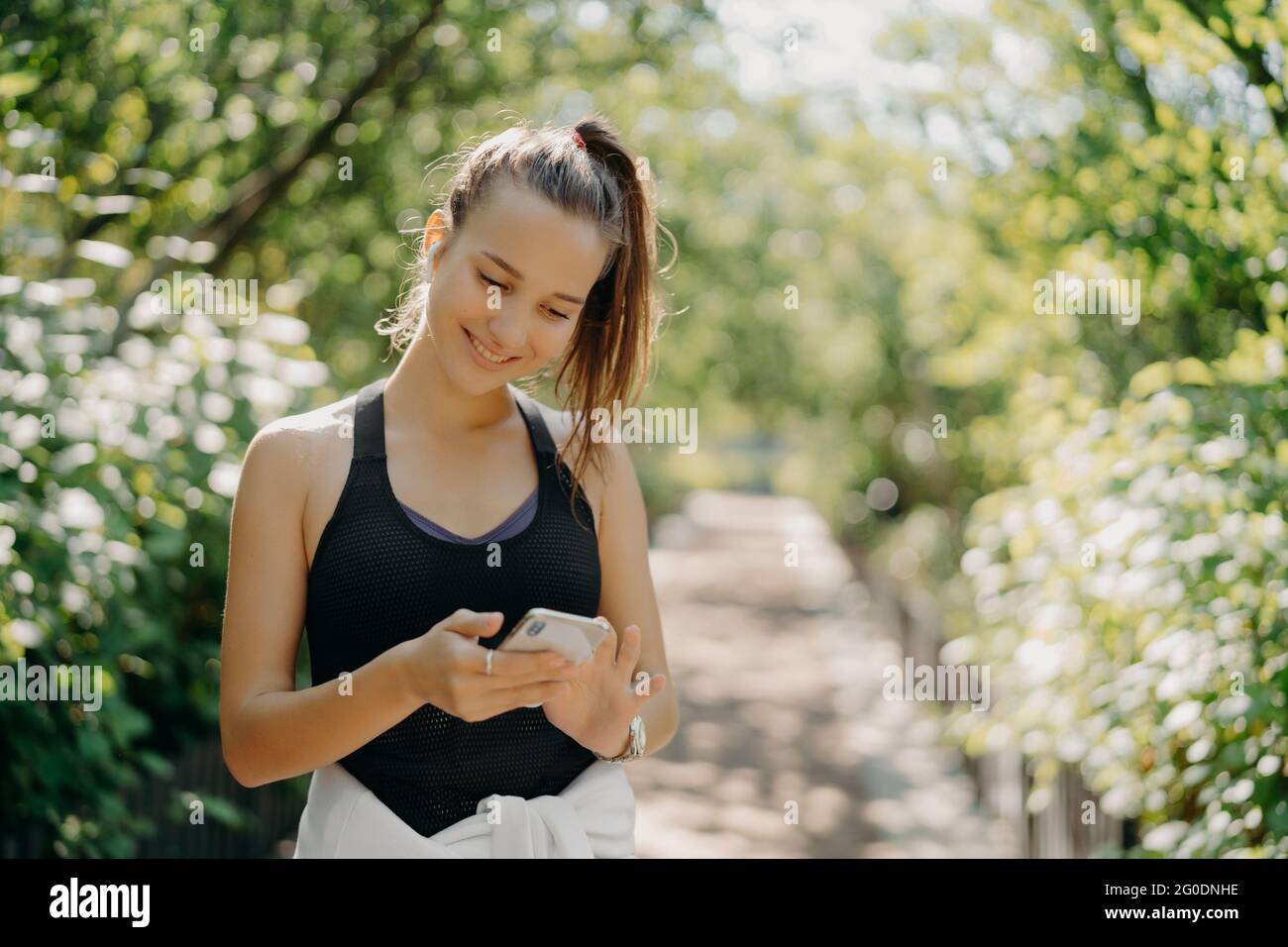 Felice atletica giovane donna utilizza smartphone sport tracker applicazione utilizza dispositivi moderni per la salute e fitness essere intelligente circa l'allenamento pose Foto Stock