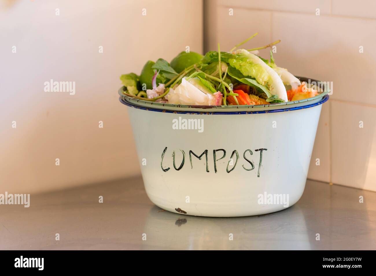 Un vecchio bacino di smalto etichettato composto e pieno di scarti vegetali pronti per il compostaggio Foto Stock