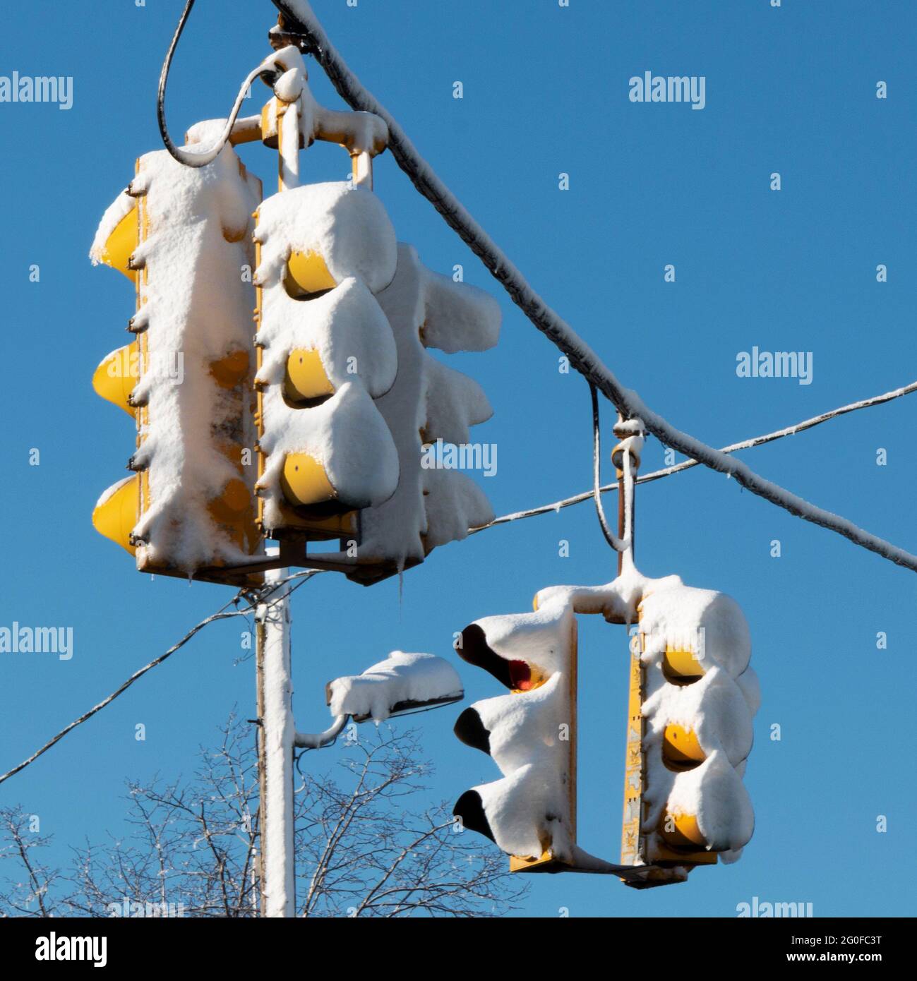 Condizioni pericolose con semafori coperti di neve dopo una tempesta di neve con cielo blu profondo sullo sfondo. Foto Stock