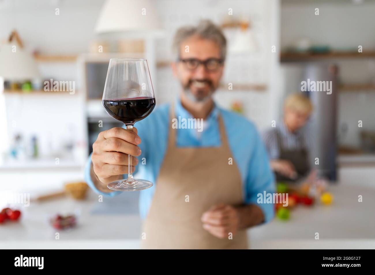 Felice coppia senior che cucinano insieme e bevono vino a casa cucina Foto Stock