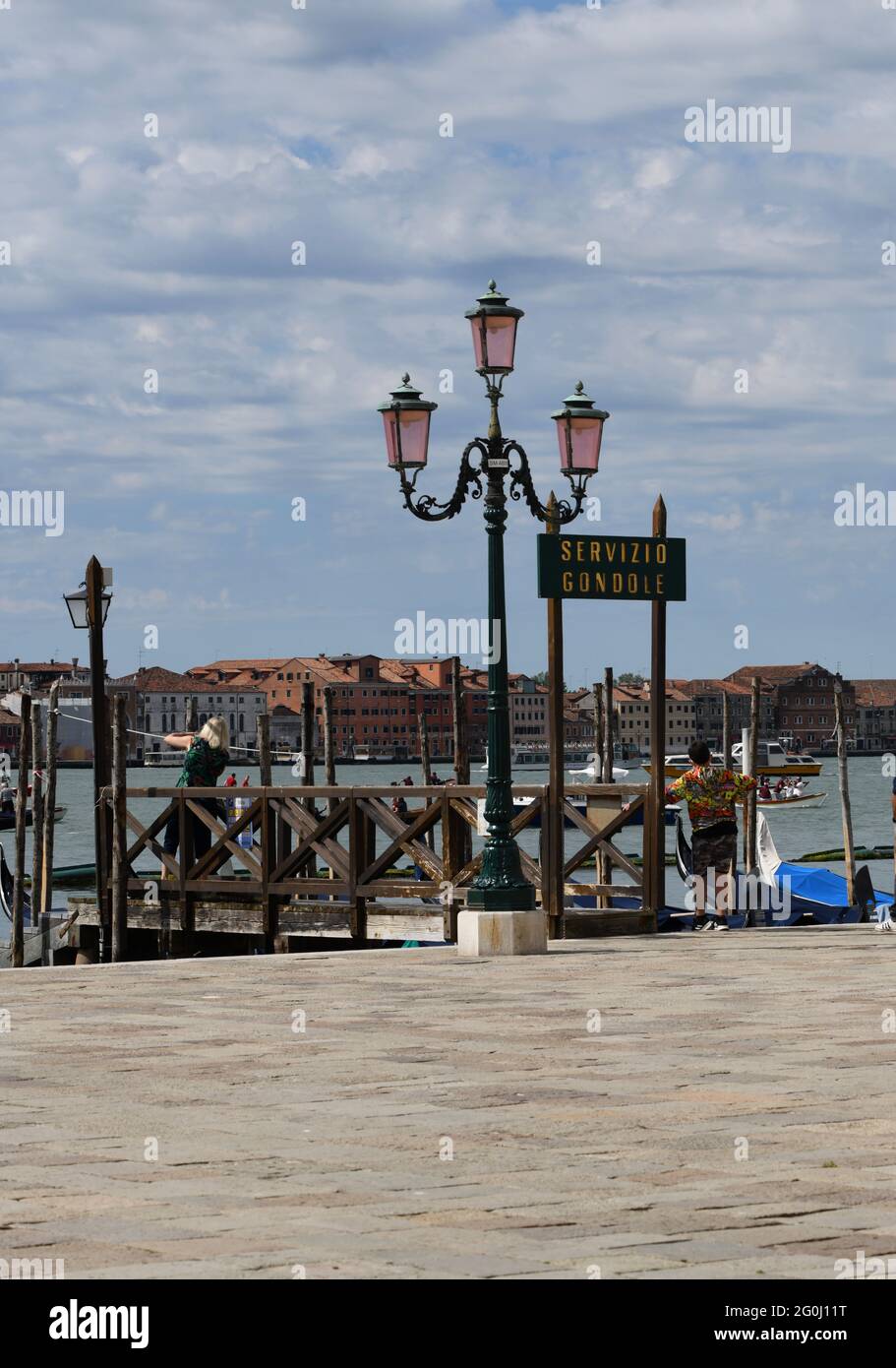 Strassenlaterne am Eingang zum Markusplatz in Venedig neben einer menschenleeren Anlegestelle gegen den bewölkten Himmel Foto Stock