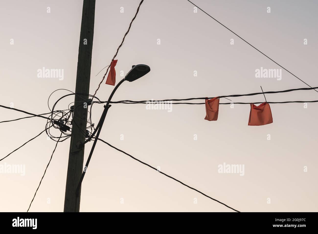 Vista ad angolo basso di bandiere arancioni sui fili elettrici provenienti da un palo lampione. Contrassegna i cavi sospesi. Foto Stock