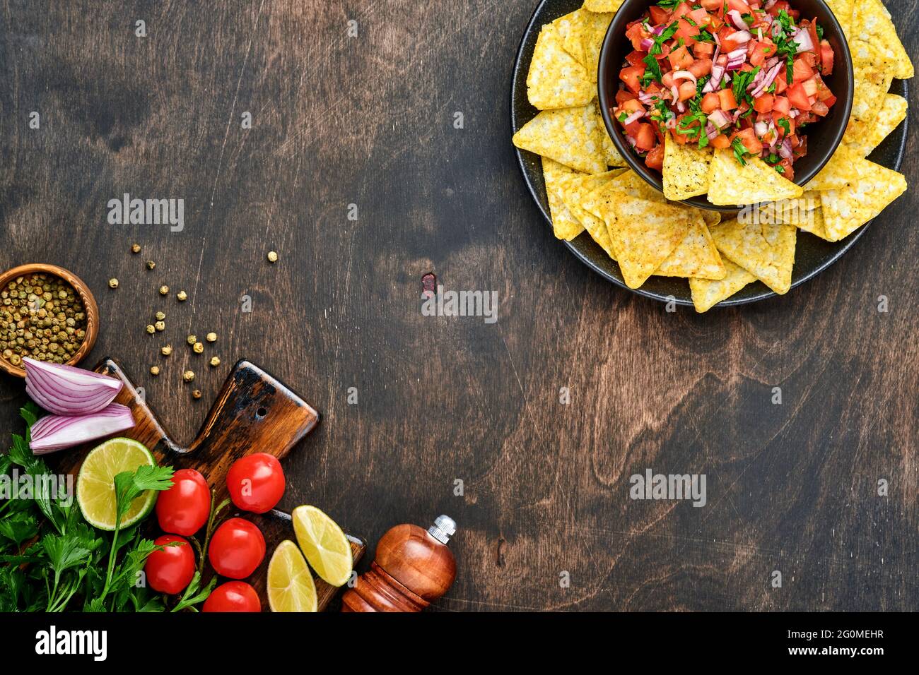 Salsa di pomodoro tradizionale messicana con nachos e ingredienti pomodori, cile, aglio, cipolla su sfondo scuro vecchio legno. Concetto di Amer Latina Foto Stock