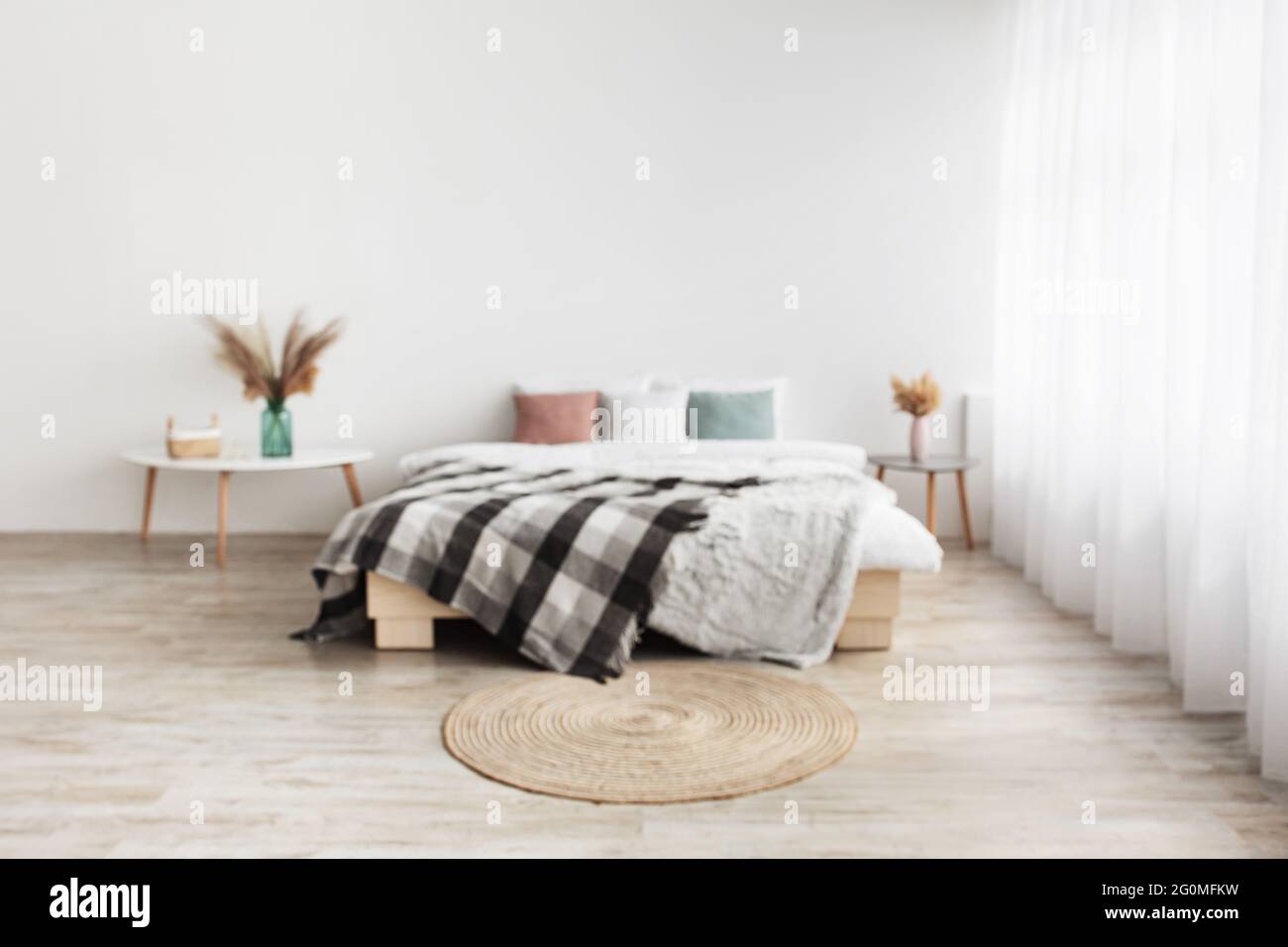 Blog su interni di casa e design accogliente. Letto matrimoniale con cuscini e coperta, tavoli con piante secche in vasi Foto Stock