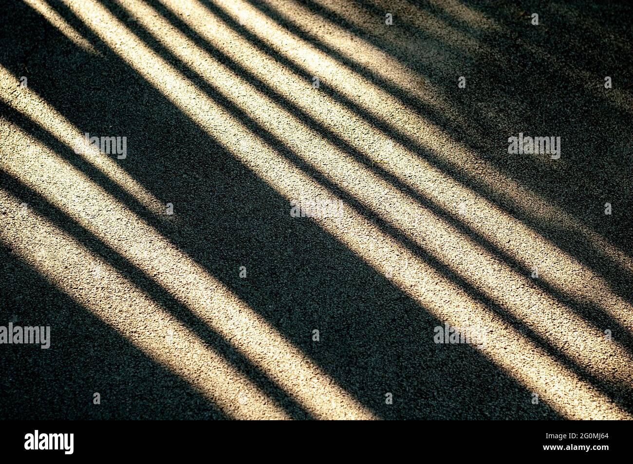Luce solare intensa e ombre nere dure sulla strada. Strisce d'ombra su una strada asfaltata. Foto Stock