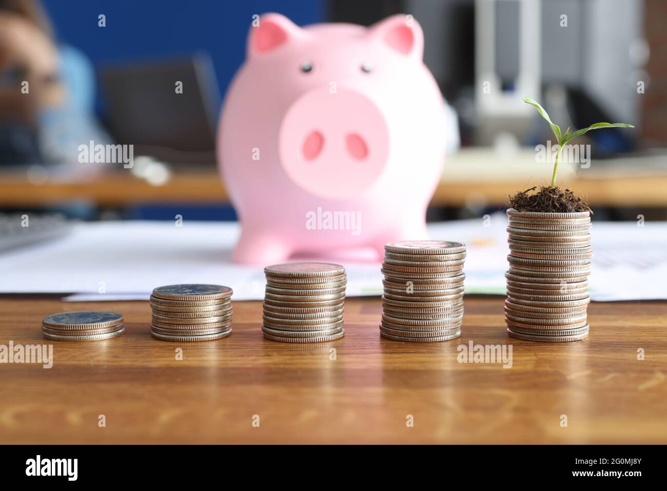 Pile di monete e di porcellini sono sul tavolo Foto Stock