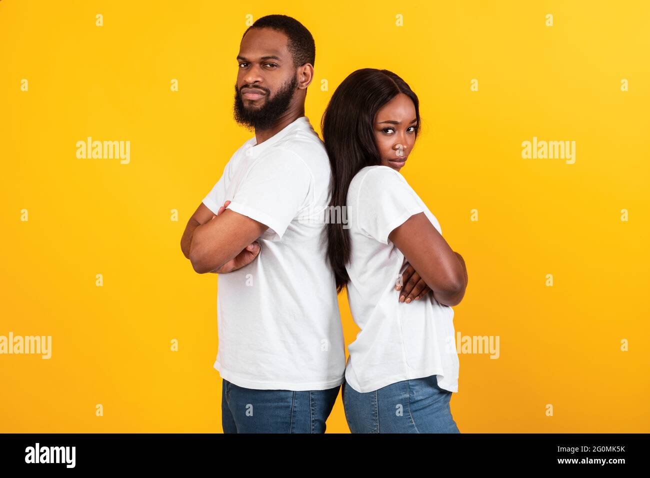 Una coppia afro che si erge dietro la schiena, parete gialla arancione dello studio Foto Stock