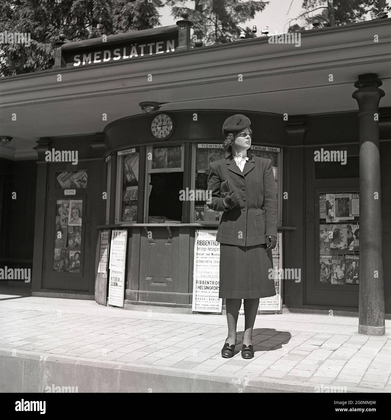 Negli anni '40. Una ragazza ben vestita sta in piedi alla stazione del tram guardando lungo le piste per vedere se sta arrivando o no. L'anno è il 1944 e i giornali in background hanno titoli che raccontano la seconda guerra mondiale, Ribbentrop in Helsink ecc. Svezia 1944 rif K71-1 Foto Stock
