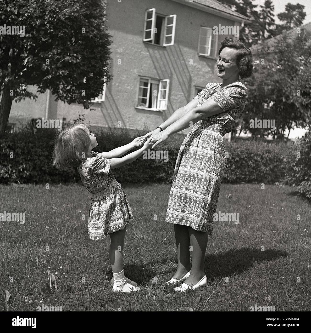 Negli anni '40. Una madre e una figlia si tengono le mani in abiti con lo stesso motivo su di loro. Il sorriso felice l'uno all'altro come lo fa questo giorno di sole 1944. Svezia 1944 rif K71-2 Foto Stock