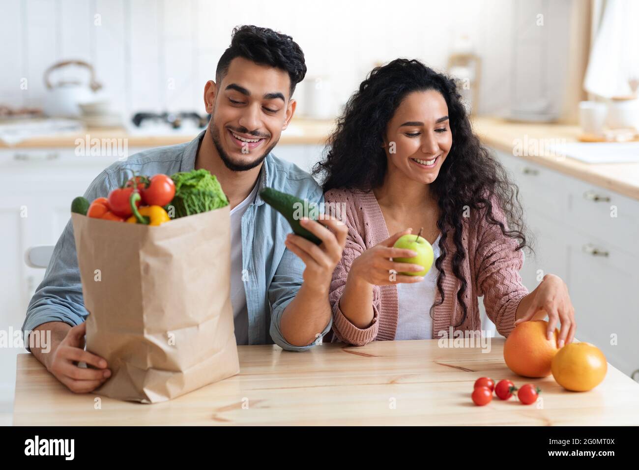 Nutrizione sana. Happy Arab coniugi Disimballaggio sacchetti di carta dopo acquisti alimentari Foto Stock