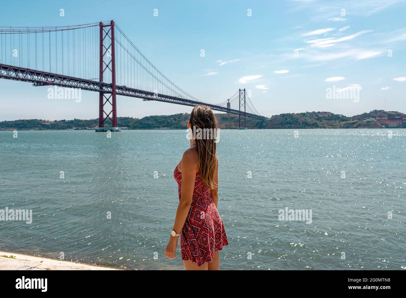 Ponte del 25 aprile e fiume Tago o Tejo dal Monumento scoperte. Felice donna turistica a braccia aperte alla piattaforma Padrao dos Descobrimentos. Belem Foto Stock
