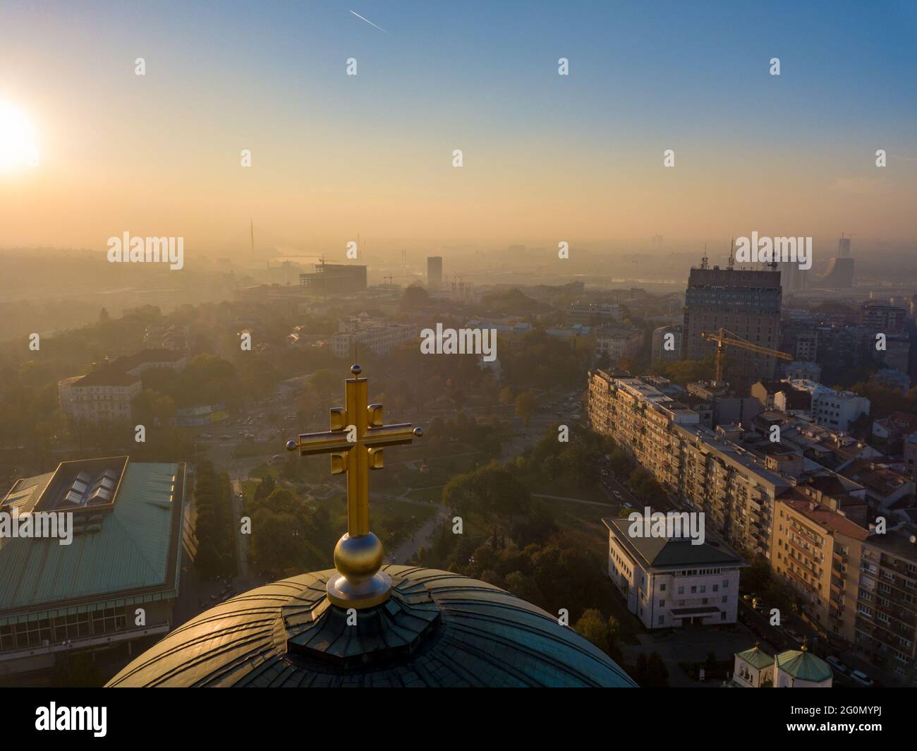 Foto aerea della croce dorata sulla cima della cupola del tempio di San Sava a Belgrado con inquinamento atmosferico sullo sfondo Foto Stock