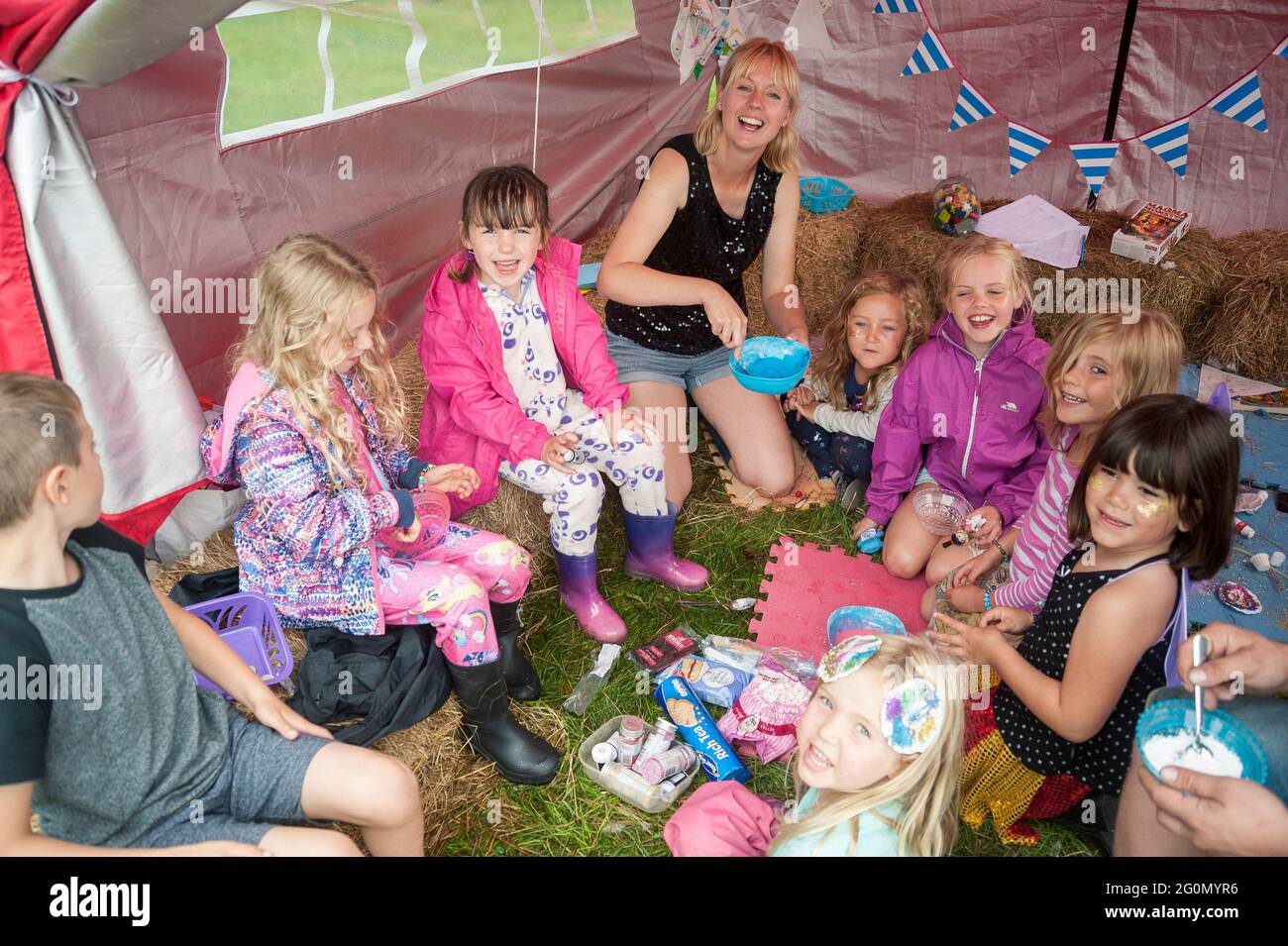 I bambini in una tenda in un festival di famiglia escono dalla pioggia e si parcheggia in un'attività Foto Stock