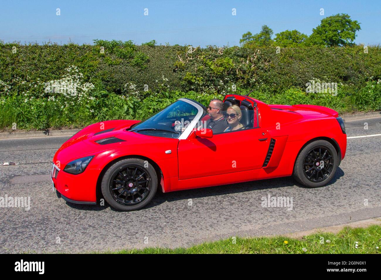 2005 Red Vauxhall Vx220 Turbo Red Roadster, benzina 1998cc, guida su strade di campagna lungo il tragitto per Capesthorne Hall, mostra di auto classiche a Cheshire, Regno Unito Foto Stock