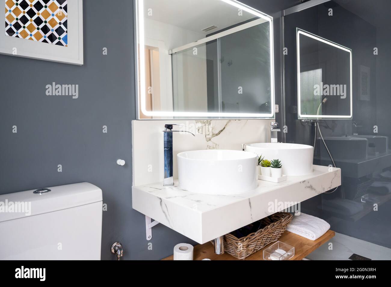 Interno di bagno luminoso e moderno con specchio con luce Foto Stock