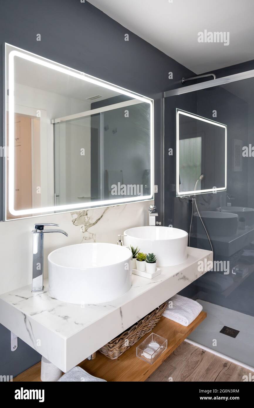 Interno di bagno luminoso e moderno con specchio con luce Foto Stock