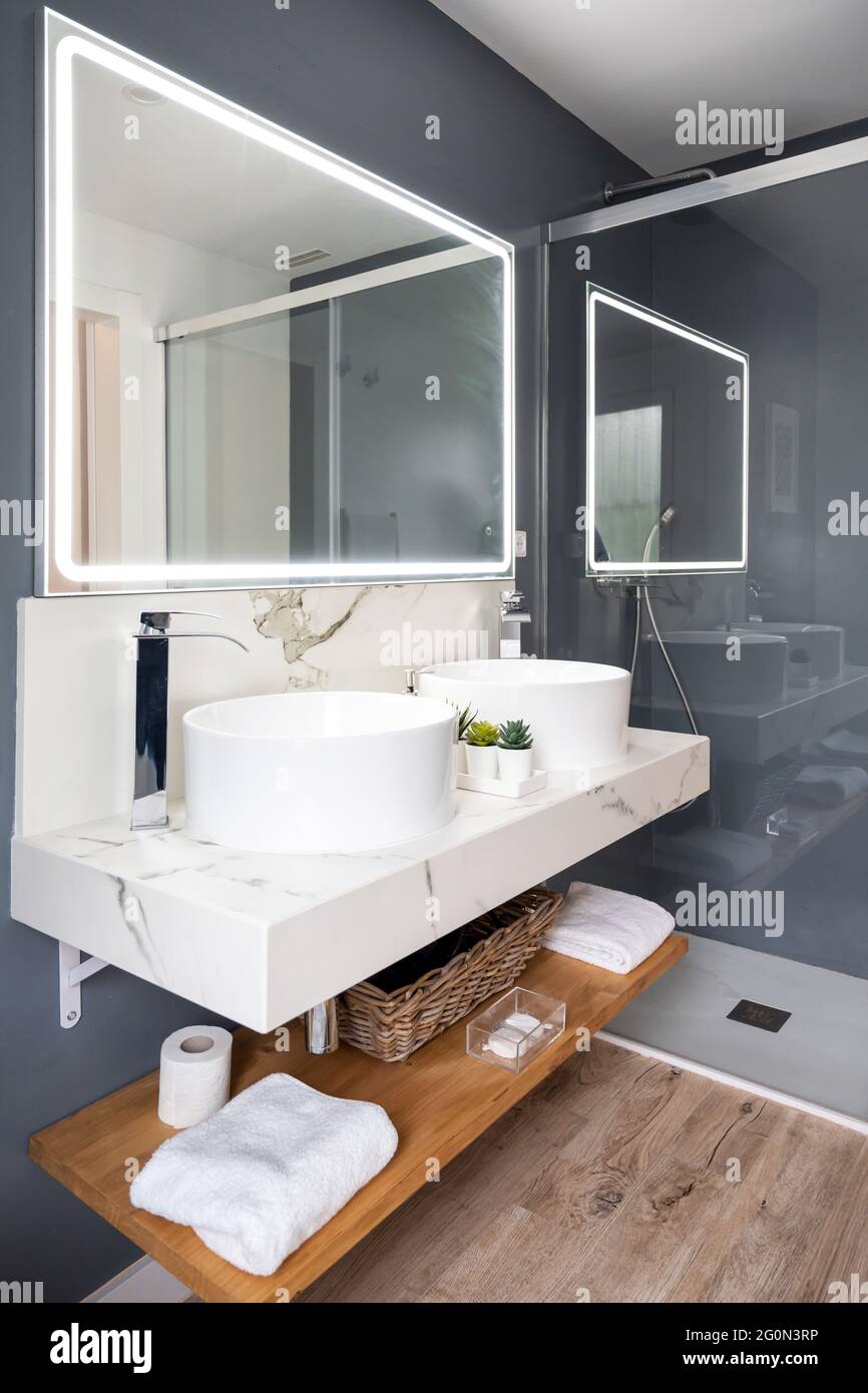 Interno di bagno luminoso e moderno con specchio con luce Foto Stock