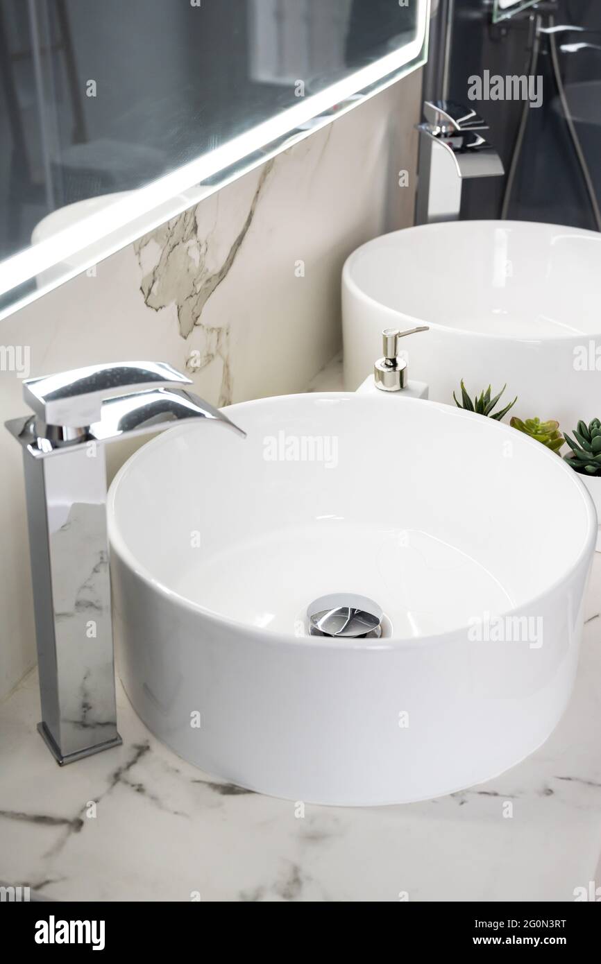 Due lavandini in ceramica all'interno di un bagno moderno e luminoso con specchio luminoso Foto Stock