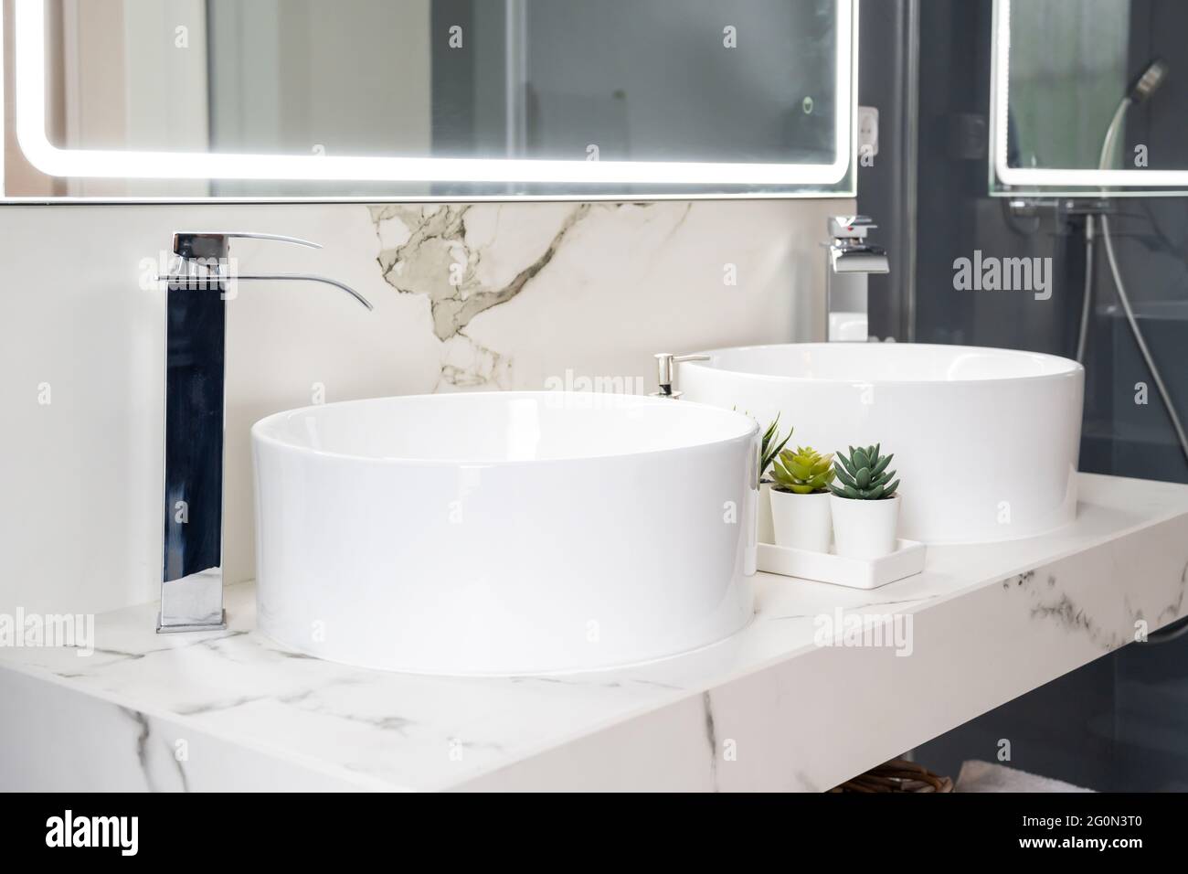Due lavandini in ceramica all'interno di un bagno moderno e luminoso con specchio luminoso Foto Stock