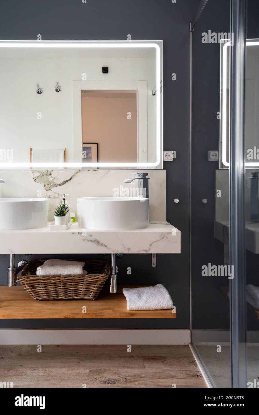 Interno di bagno luminoso e moderno con specchio con luce Foto Stock