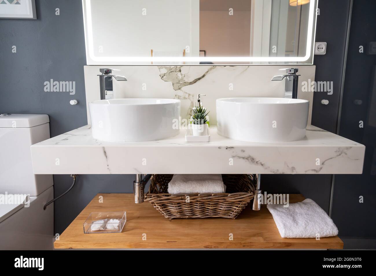 Interno di bagno luminoso e moderno con specchio con luce Foto Stock