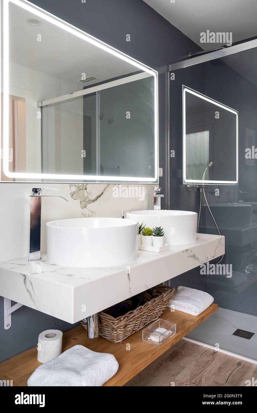 Interno di bagno luminoso e moderno con specchio con luce Foto Stock