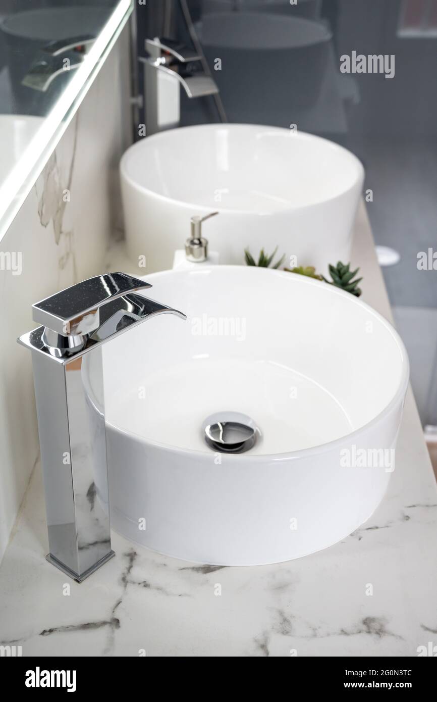 Due lavandini in ceramica all'interno di un bagno moderno e luminoso con specchio luminoso Foto Stock