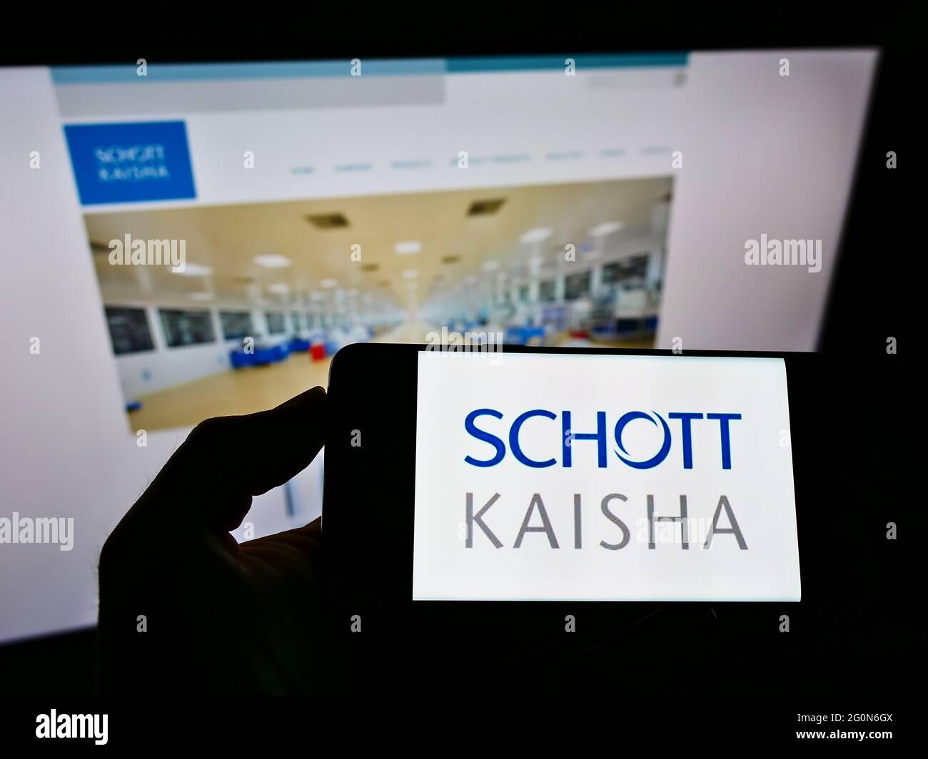 Persona titolare smartphone con logo della società indiana di confezionamento Schott Kaisha Pvt. Ltd. Sullo schermo davanti al sito Web. Mettere a fuoco il display del telefono. Foto Stock