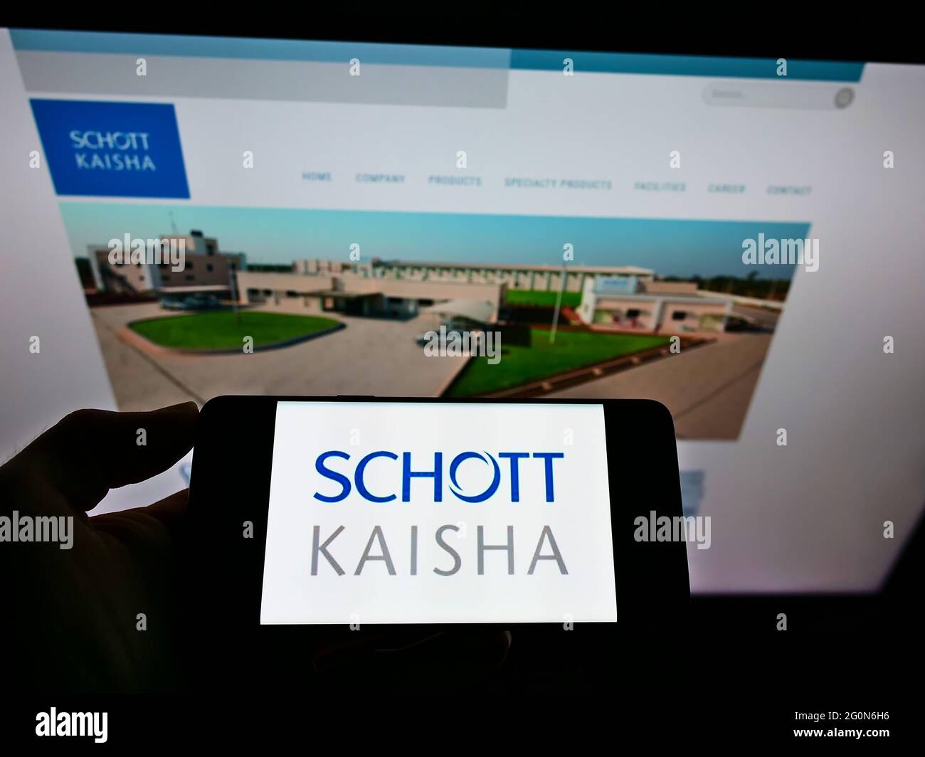 Persona che tiene il cellulare con il logo della società indiana di imballaggio Schott Kaisha Pvt Ltd sullo schermo di fronte alla pagina web aziendale. Mettere a fuoco il display del telefono. Foto Stock