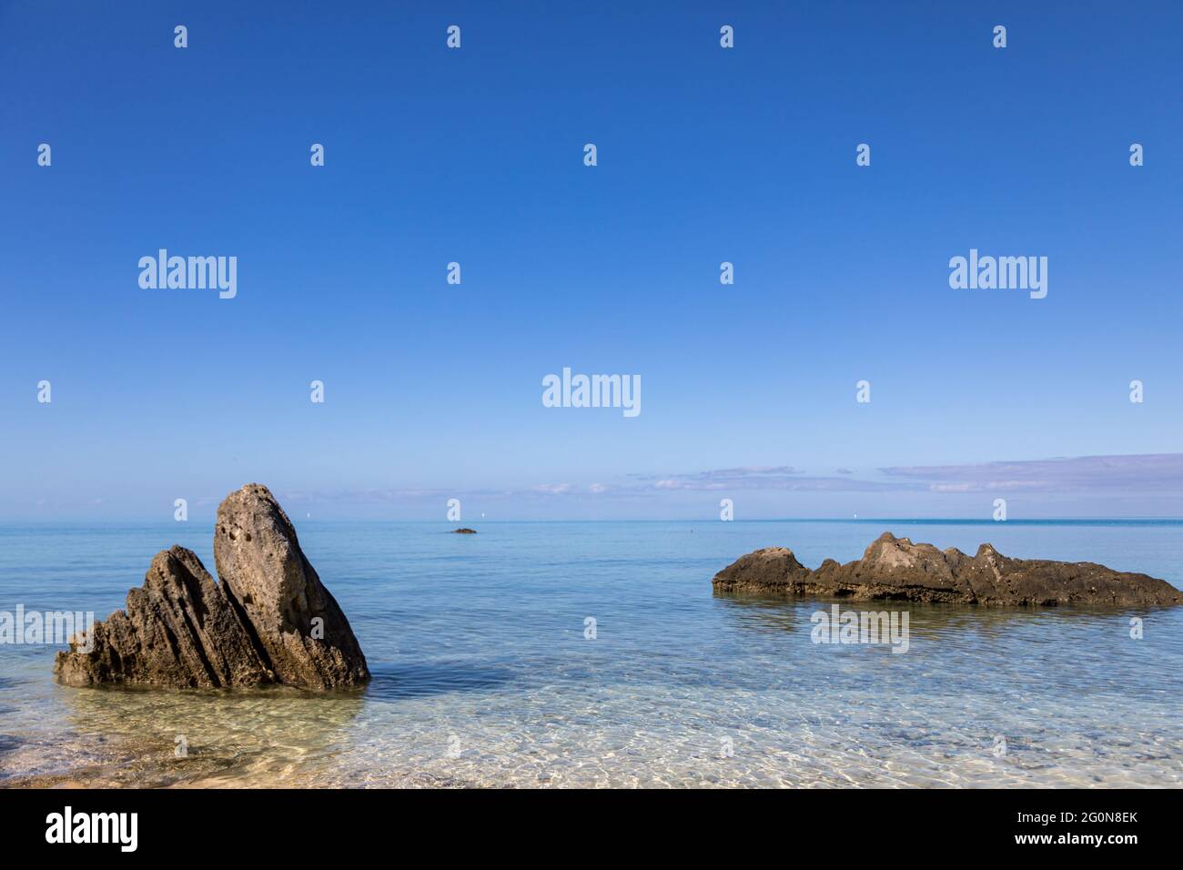 Grande affioramento roccioso su una spiaggia tranquilla, cielo blu calmo e scena oceanica Foto Stock