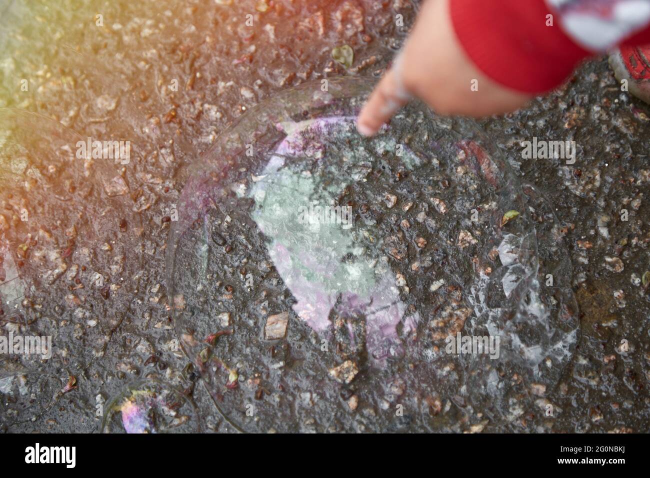 La mano del bambino punta a una bolla di sapone. Curiosità e concetto di esplorazione del mondo. Foto Stock
