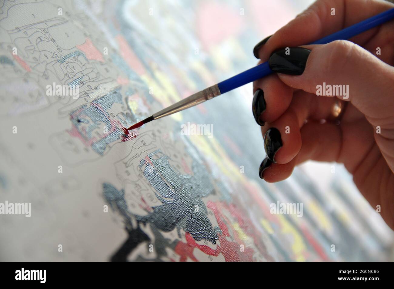 Pittura per numeri. La mano tiene una spazzola e vernici. Foto Stock