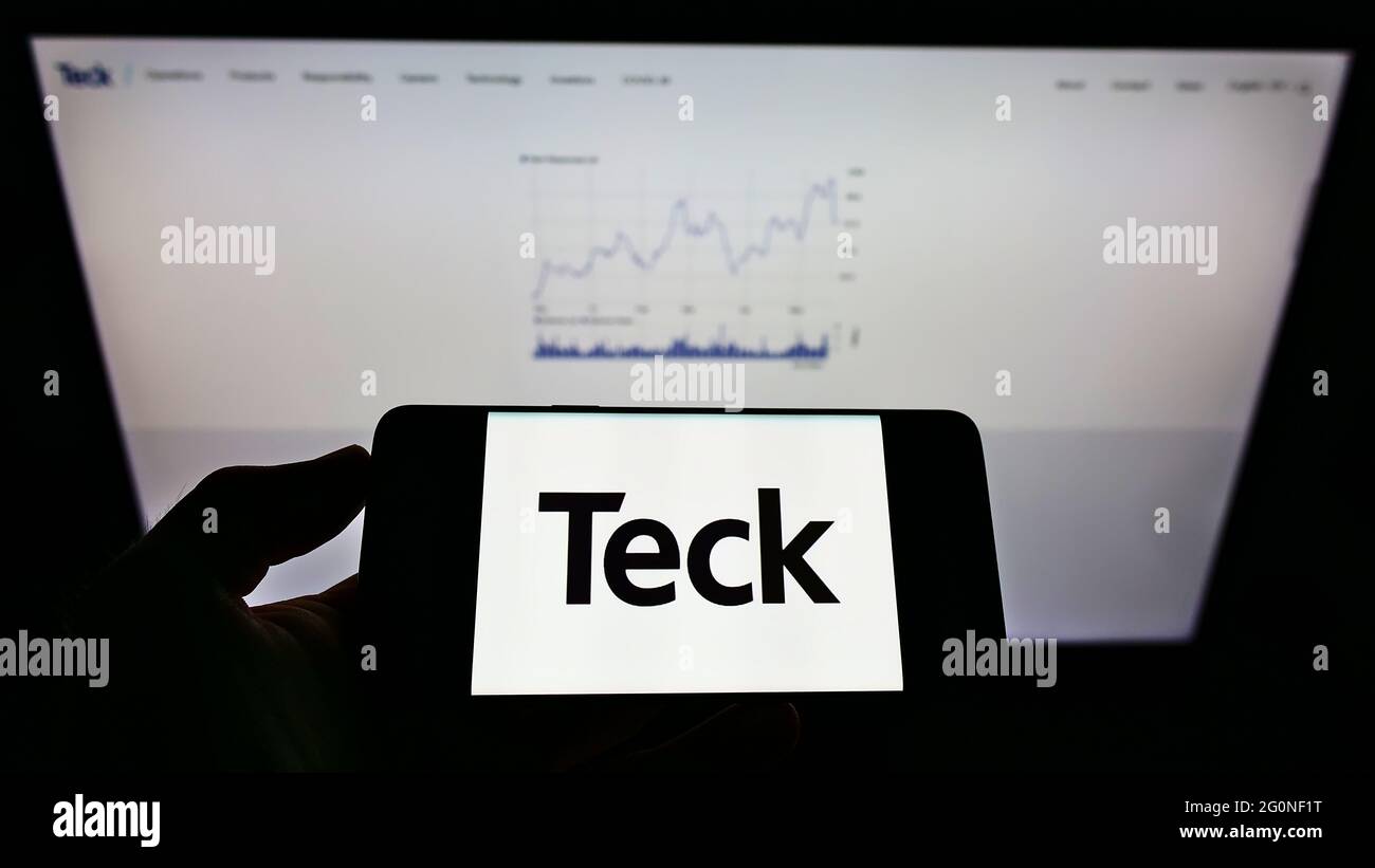 Persona che tiene il cellulare con il logo della società mineraria canadese Teck Resources Limited sullo schermo davanti alla pagina web. Mettere a fuoco il display del telefono. Foto Stock