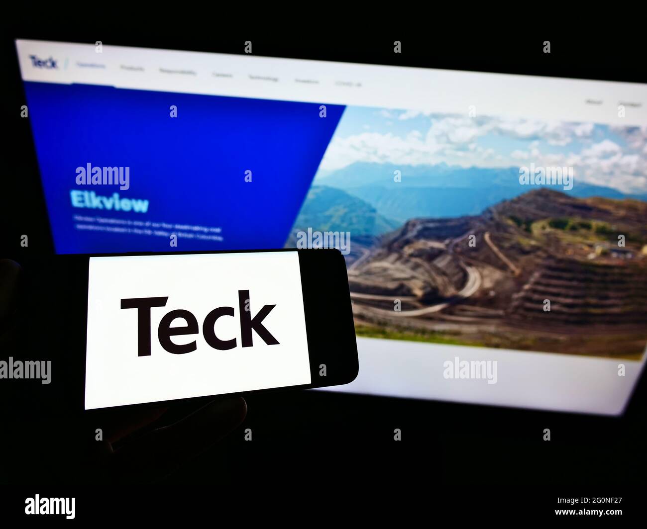 Persona che tiene il cellulare con il logo della società mineraria canadese Teck Resources Ltd sullo schermo di fronte alla pagina web aziendale. Mettere a fuoco il display del telefono. Foto Stock
