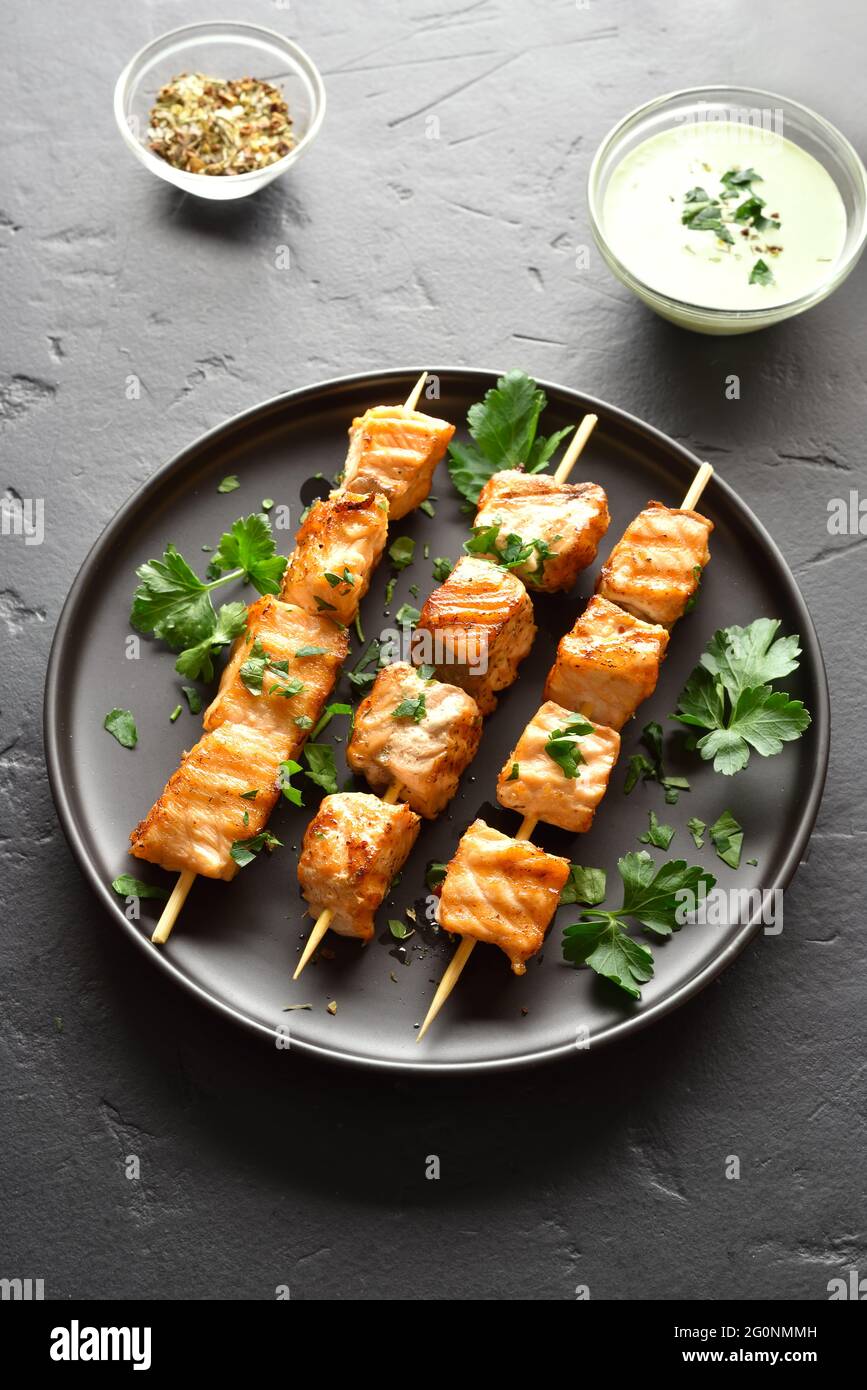 Salmone alla griglia kebab. Barbecue spiedini di salmone su pietra nera dello sfondo. Foto Stock