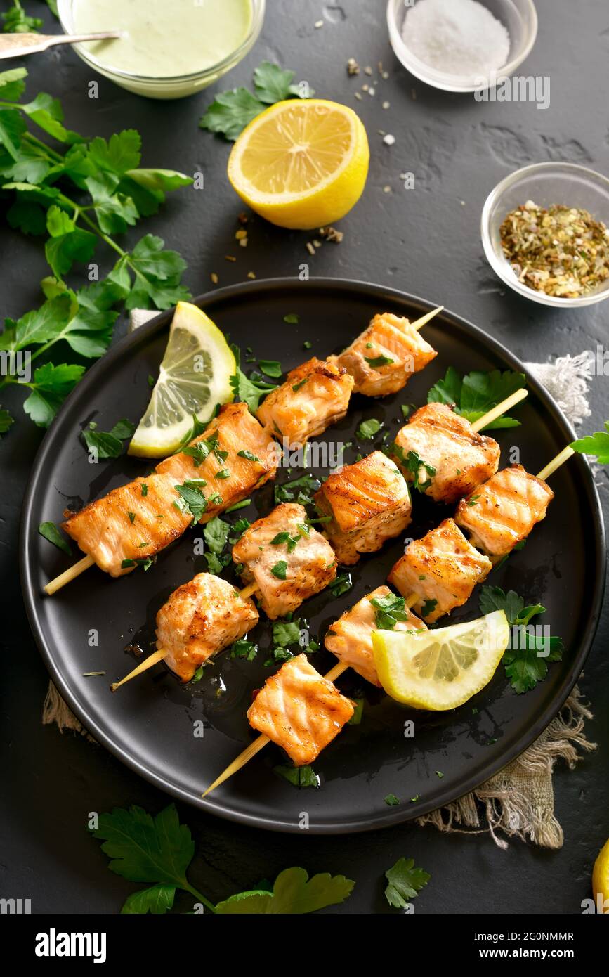 Salmone alla griglia kebab. Barbecue spiedini di salmone su pietra nera dello sfondo. Foto Stock