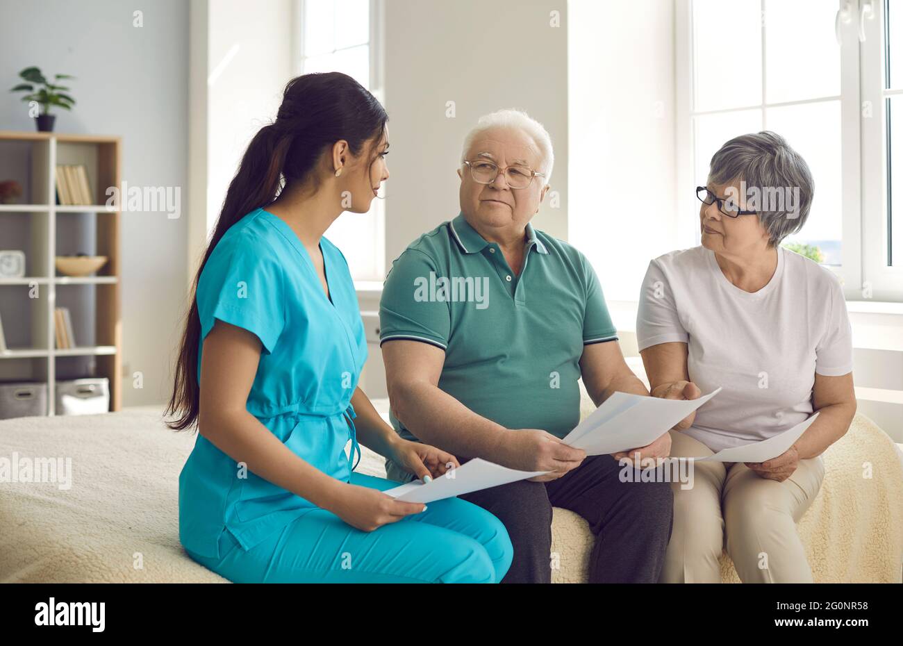 L'operatore sanitario professionale aiuta i pazienti anziani a comprendere e compilare il contratto di assistenza domiciliare Foto Stock