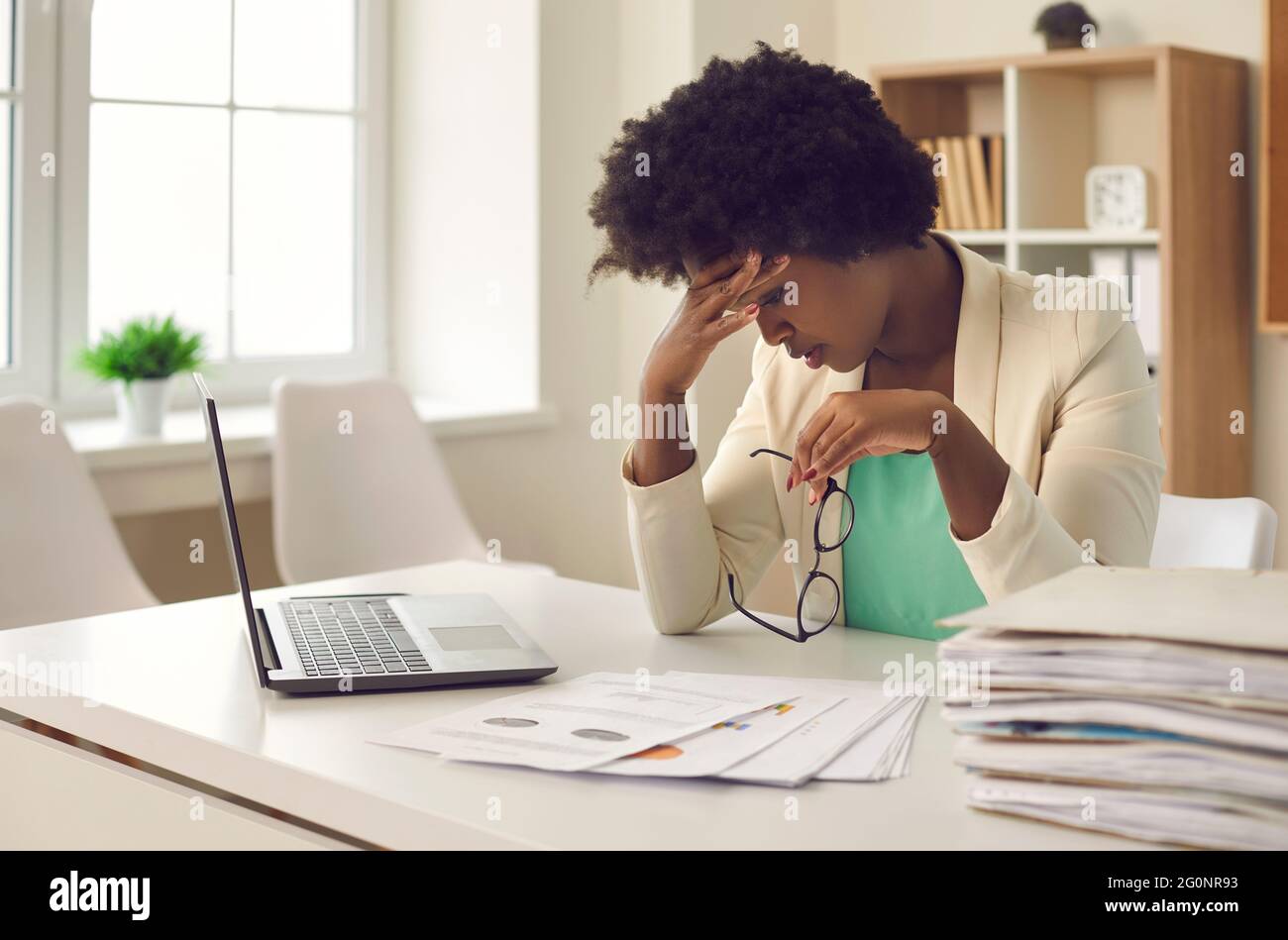 La donna d'affari afroamericana stanca delle procedure di lavoro e delle scadenze soffre di mal di testa. Foto Stock