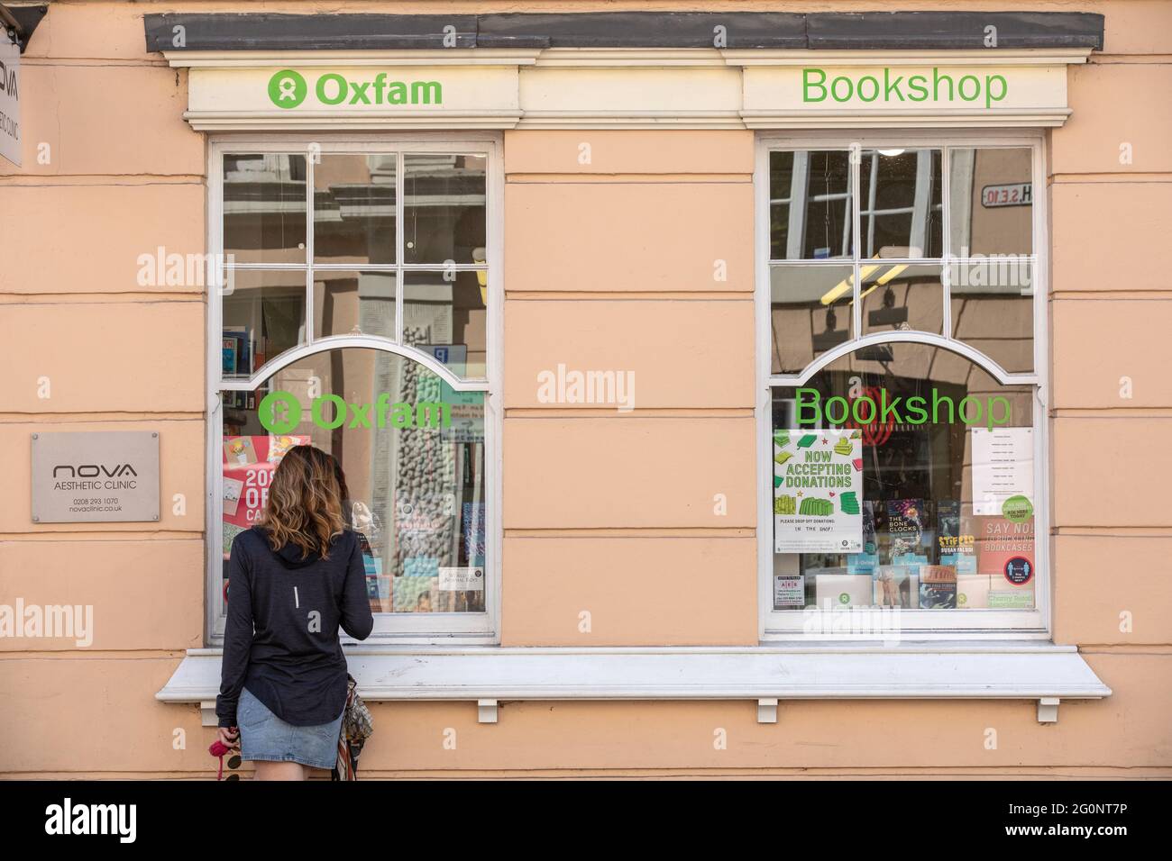Una donna che guarda una vetrina di libri Oxfam, Greenwich, Londra sud-orientale, Inghilterra, Regno Unito Foto Stock