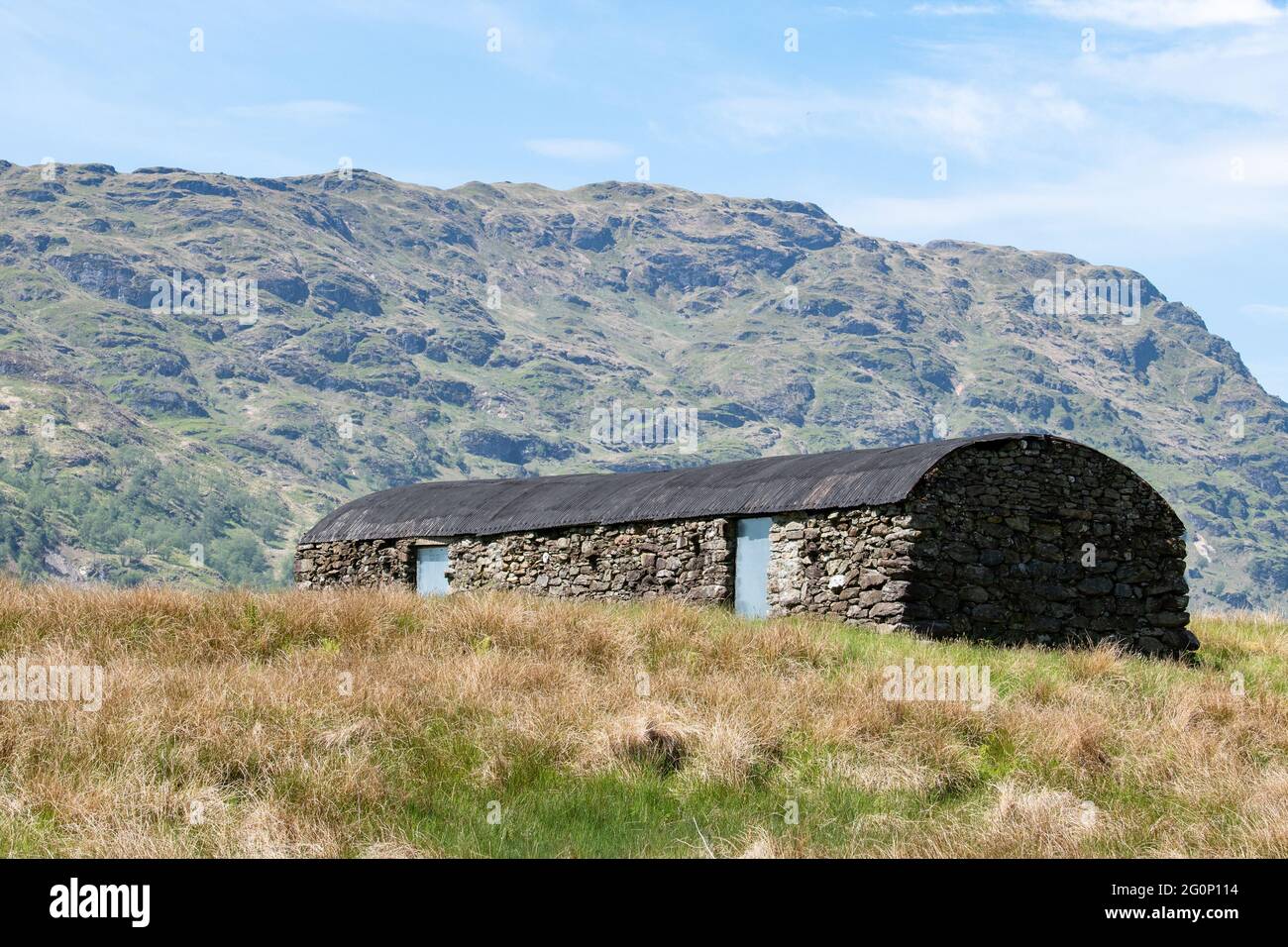 Vecchio edificio in pietra con tetto in metallo ondulato ricurvo vicino a Loch Katrine, Trossachs, Scozia, Regno Unito Foto Stock