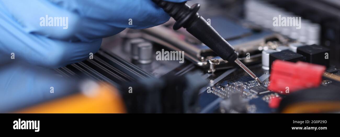 Il tecnico dei guanti con tester controlla il closeup della scheda madre Foto Stock