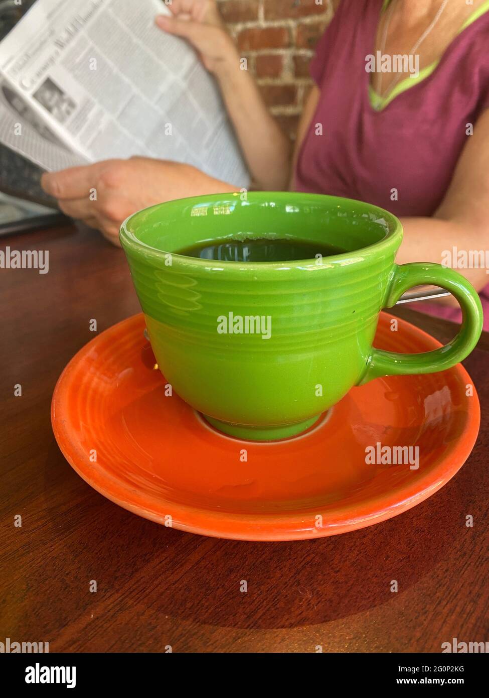 La donna si rilassa con un giornale e una tazza di caffè mentre i clienti, i caffè e i ristoranti interni iniziano a riaprire mentre le restrizioni Covid-19 cominciano a sollevare a New York City. Foto Stock