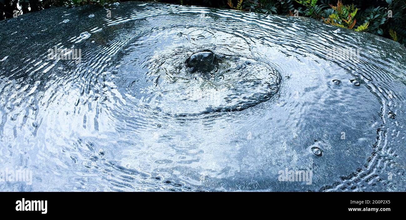 acqua che crea onde e forme circolari con bolle Foto Stock