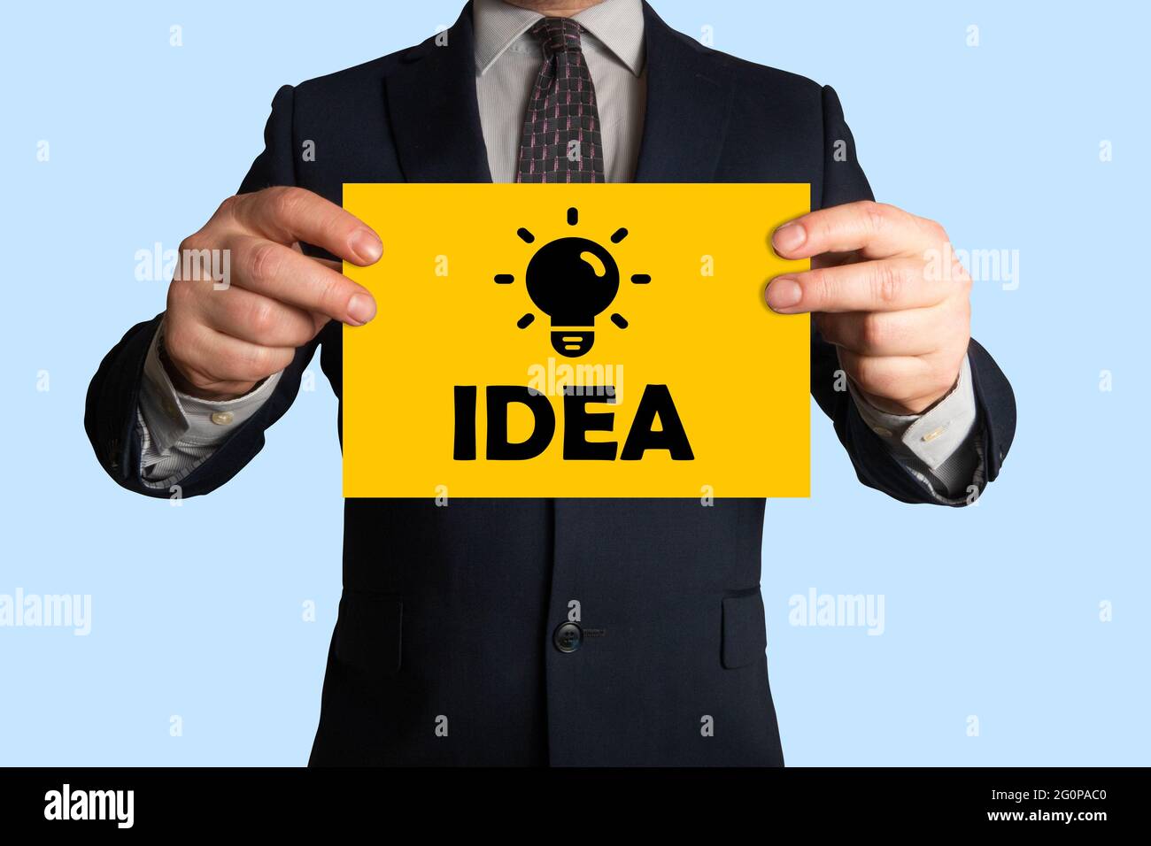 Uomo d'affari che tiene un foglio di carta con l'immagine della lampadina e dell'idea di parola, tutto che simbolizza l'idea, l'innovazione, la creatività, l'ispirazione, innovazione Foto Stock